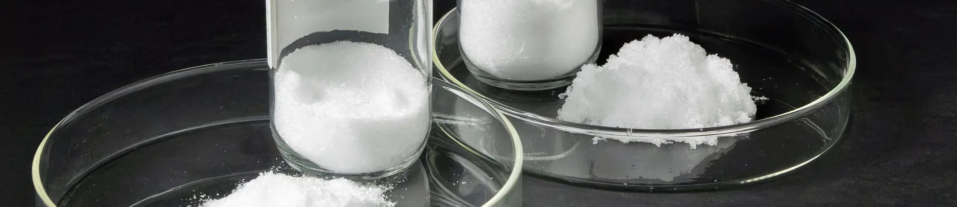 Two test dishes of white powdery substances against a black background