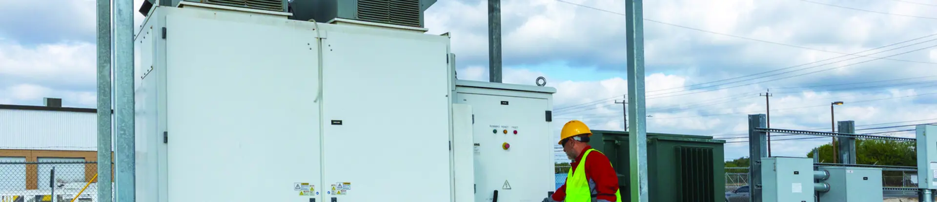 Technician outside SwRI’s on-campus 500-kilowatt-hour grid-connected Battery Energy Storage System on a cloudy day