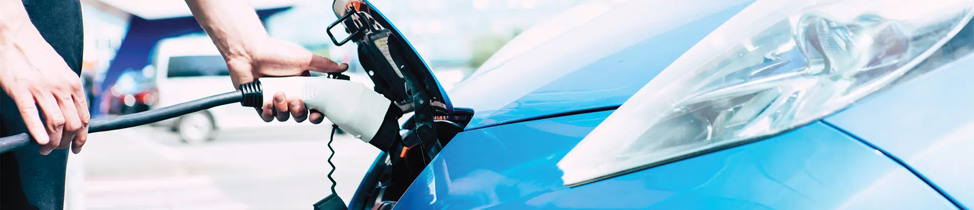 Male charging an electric car on special station outdoors