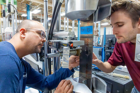 Two engineers repairing bolt holes on an aircraft