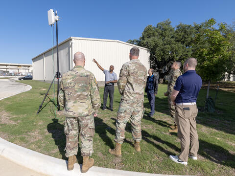 Military program managers receiving a briefing outdoors