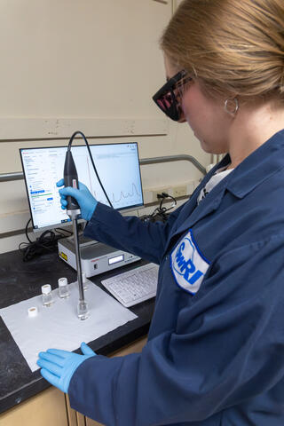 Female engineer sampling fuel with a metal wand