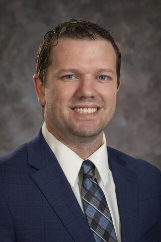 Professional portrait of Clay Weston against a grey background