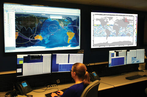 woman sitting a desk typing on keyboard while looking at several computer screens