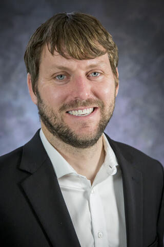 Victor Murray portrait against a blue backdrop