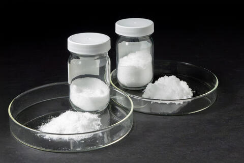 Two test dishes of white powdery substances against a black background
