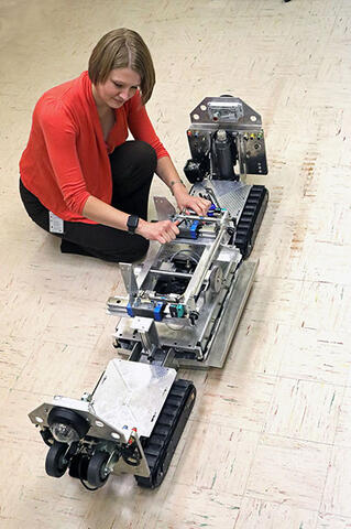 engineer looking over a robot with tank treads 