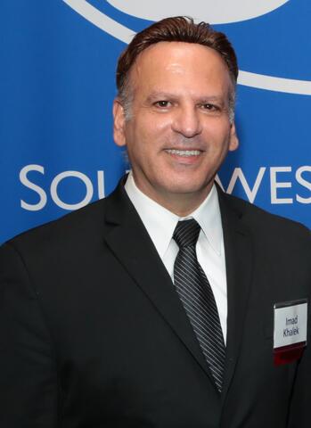 Portrait of Dr. Imad Khlaek against a blue background