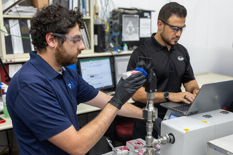 Two male engineers conducting tests with a custom model of a child's airway attached to machinery