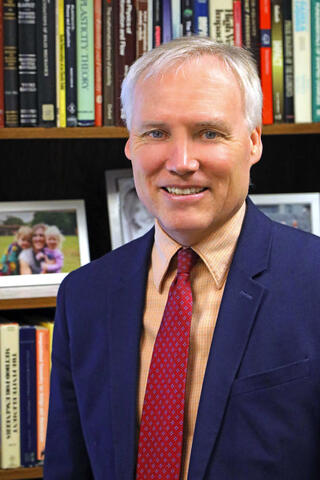 Professional portrait of Dr. James Walker in front of a book shelf