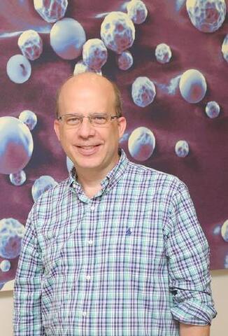 SwRI Staff Scientist Dr. Jonathan Bohmann standing in front of technical artwork