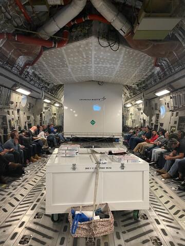 The Lucy spacecraft shipping container aboard a U.S. Air Force C-17 cargo plane accompanied by a few team members