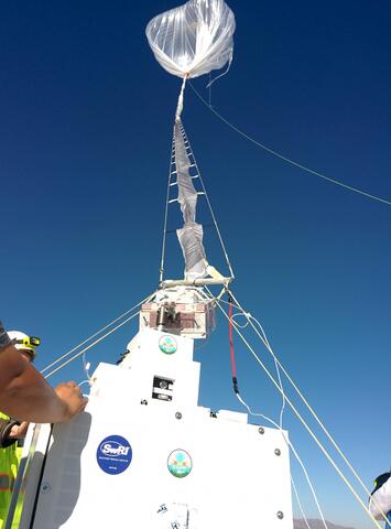 Large balloon floating above boxes holding instruments