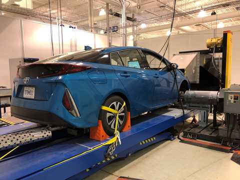 Blue car on a chassis dynamometer, interfacing with traffic simulation software to provide a controllable, repeatable environment for testing the tools developed for the Eco-Mobility with Connected Powertrains