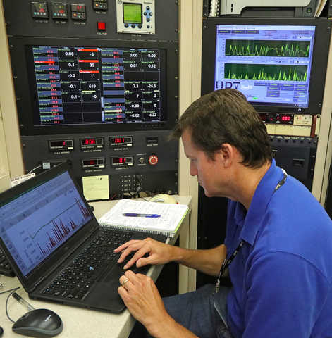 Gary Neely in a blue shirt in front of panels displaying data