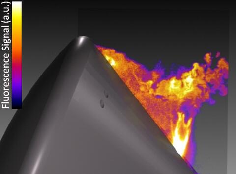 Orange, red and yellow plumes come off of a grey structure