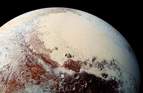 Pluto’s surface shows a remarkable range of subtle colors, digitally enhanced in this view to a rainbow of pale blues, yellows, oranges, and deep reds.