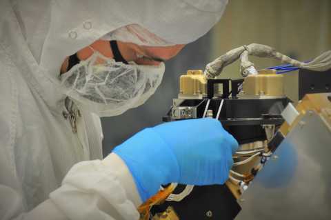 A team member in protective suit installs the scan mirror on the L’Ralph Instrument 