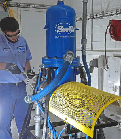 Technician makes adjustments to the heat exchanger colored blue with a white SwRI logo