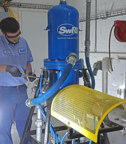 Technician makes adjustments to the heat exchanger colored blue with a white SwRI logo