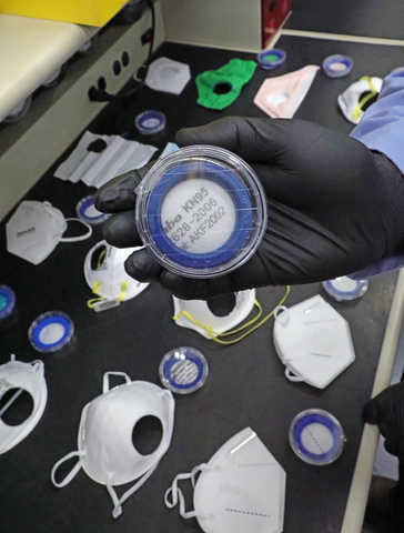Multiple mask and respirator samples with circular holes cut out for testing