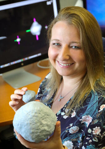 Dr. Tracy Becker holds models of asteroids