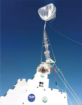 Observatory hanging below a balloon with blue sky in the background