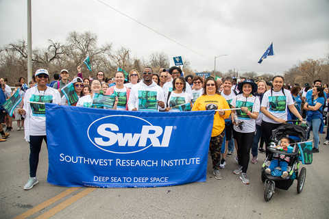 SwRI employees wearing MLK shirts standing behind a blue Southwest Research Institute banner 