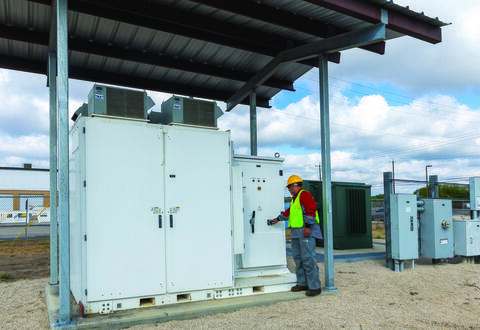 Technician outside SwRI’s on-campus 500-kilowatt-hour grid-connected Battery Energy Storage System on a cloudy day