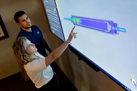 Dr. Raouf Tajik and Jacqueline Manders discuss computational fluid dynamics model for virtual evaluations pointing to a computer screen