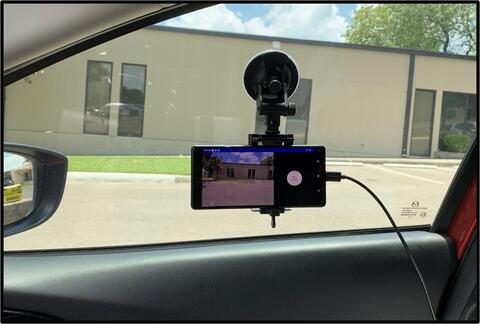 A cellular phone mounted on a windshield, view from within the vehicle looking out of the windshield 