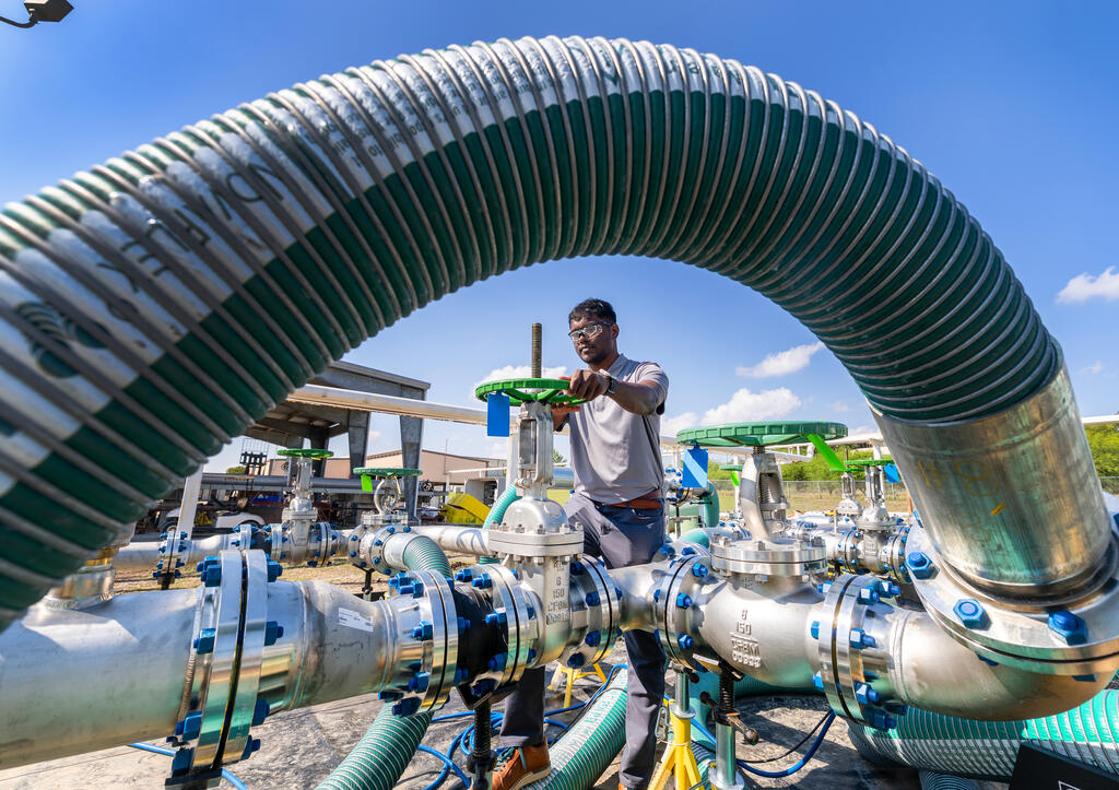 Close up photo of heat exchanger test loop with SwRI staff member framed underneath the loop