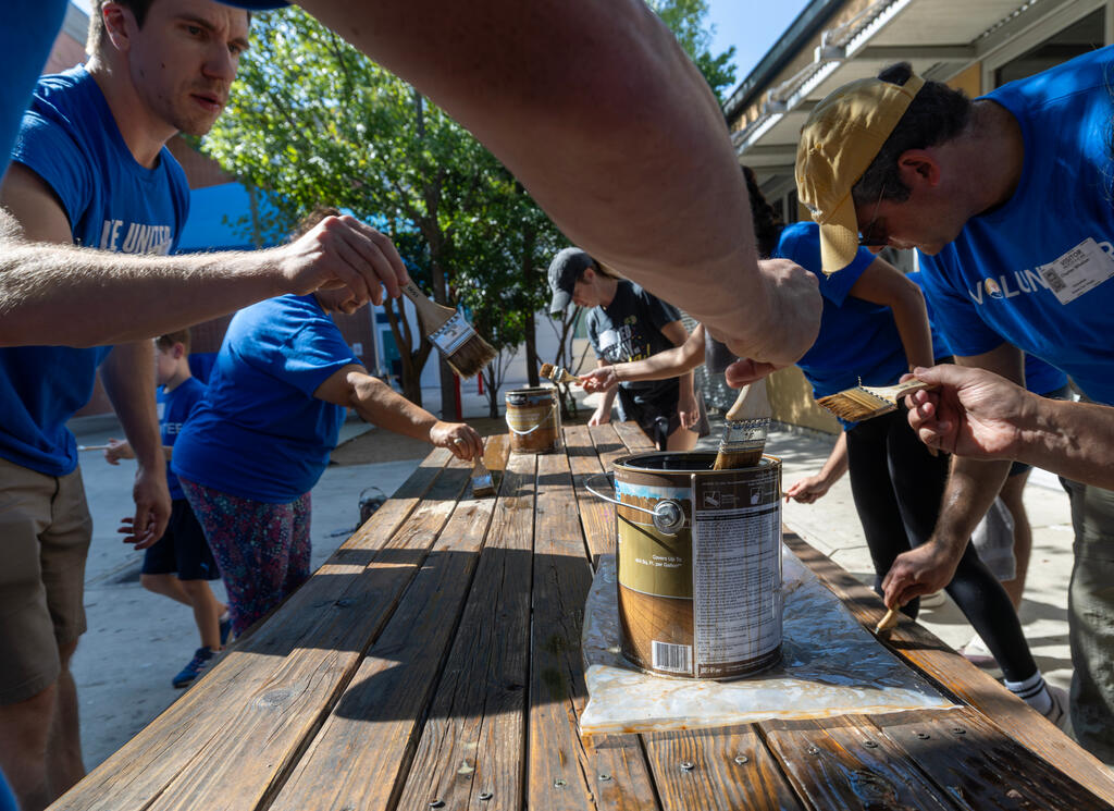 SwRI staff members surrounding a picnic table revarnishing at Haven for Hope