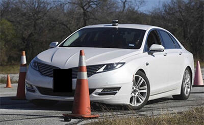 white sedan navigating traffic cones on road