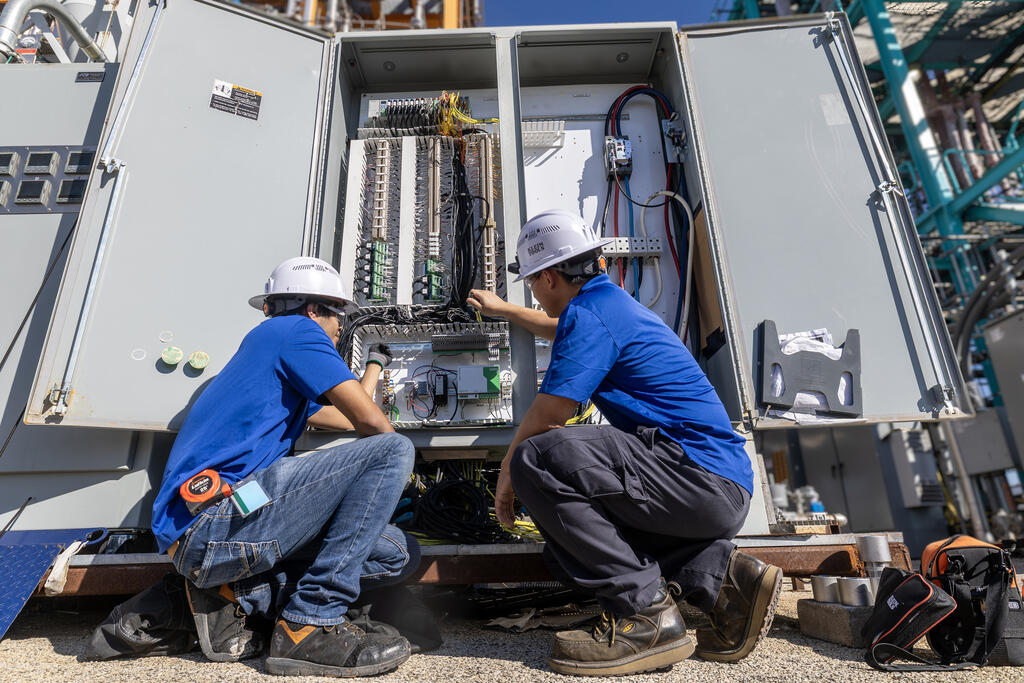 Two technicians squatting, working at pilot plant