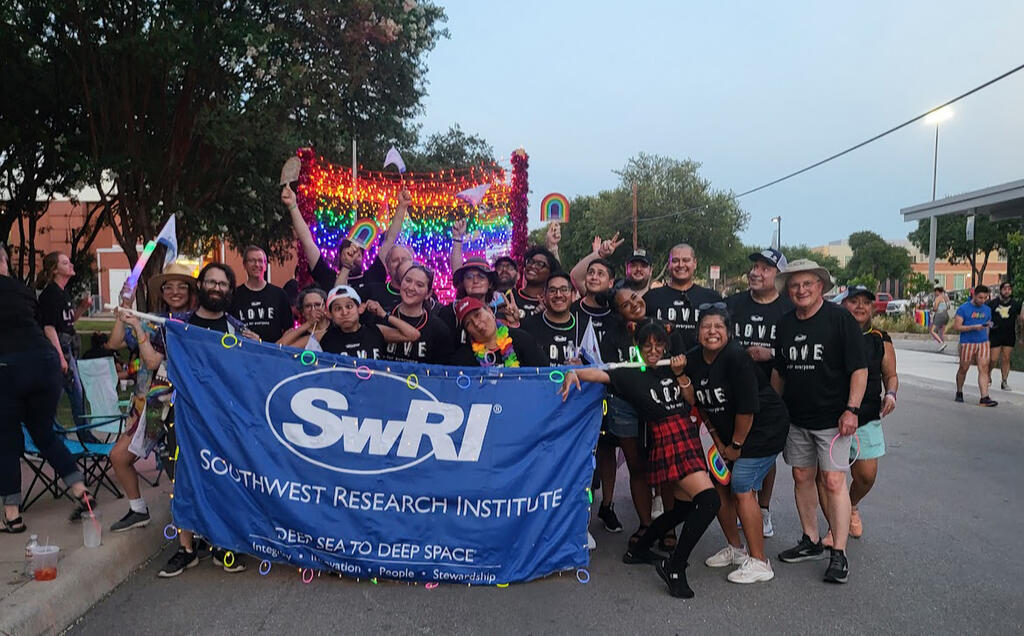 SwRI employees wears LOVE shirts holding a blue Southwest Research Institute banner