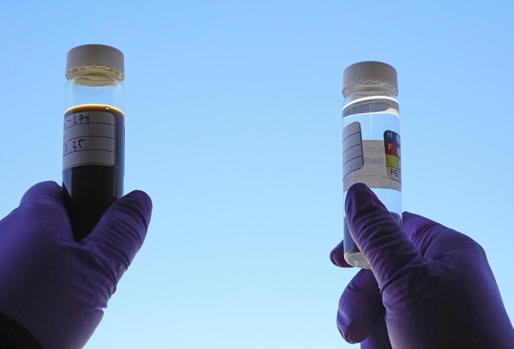 SwRI staff member holding up two vials of distillation of alternative fuels