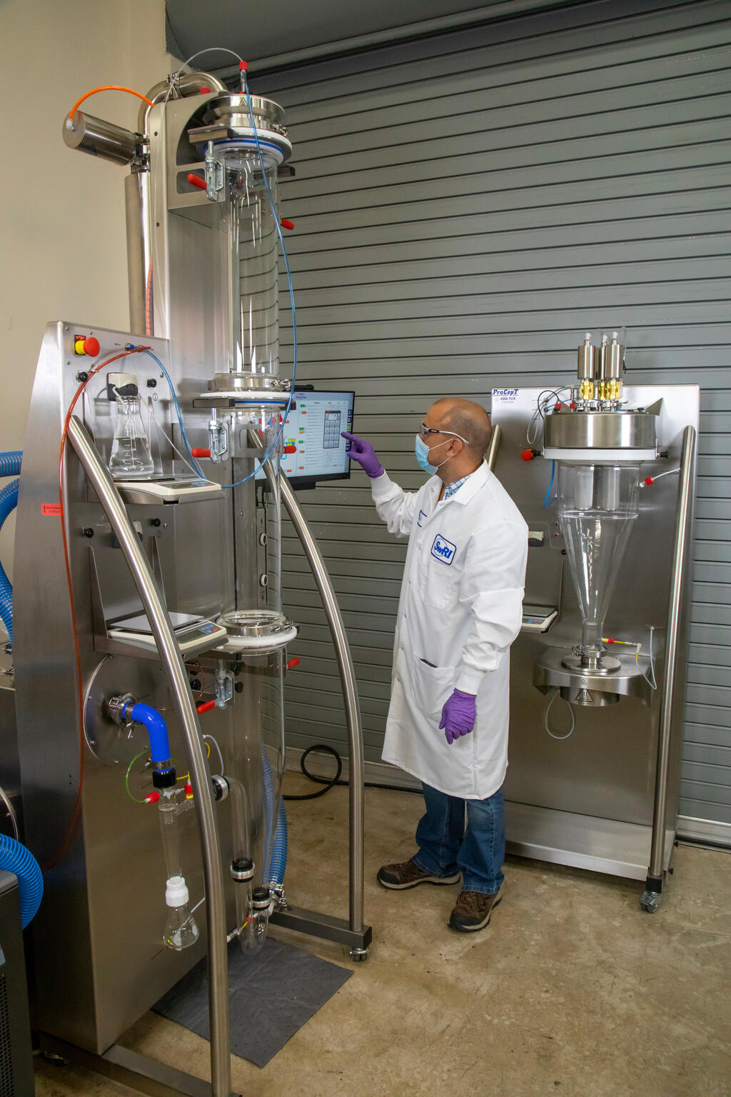 SwRI staff using spray dryer with bed coater in background