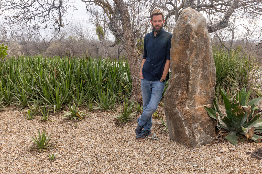 Adam Cawood leaning against rock formation in the desert 