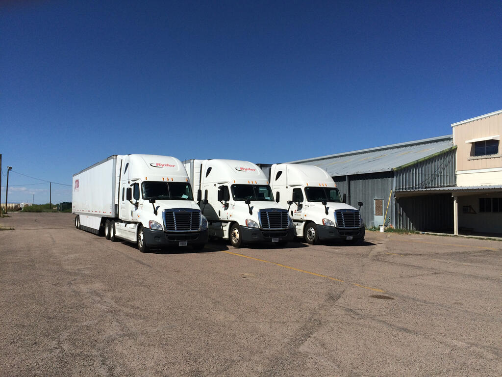 Three white semi-trucks parked out side SwRI lab