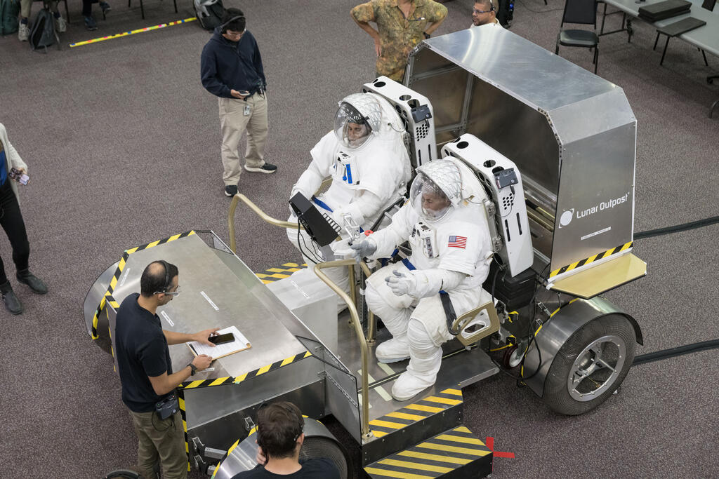 Lunar Rover with two people dressed in space suits driving the rover