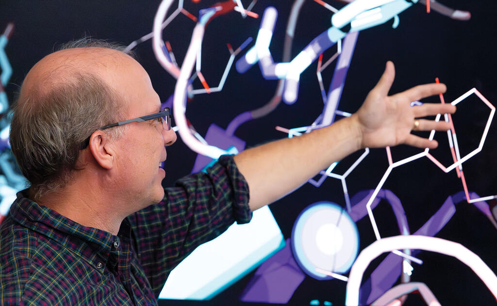 Man speaking to SwRI's Rhodium drug development software projected on a screen