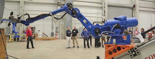 Engineers in a lab demonstrating a blue robot