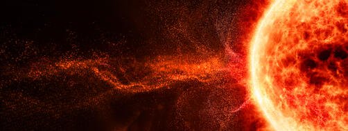 Glowing orange sun with solar flare particles against black space