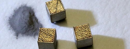 Metal powder in a pile on the left, three small metal cubes on the right