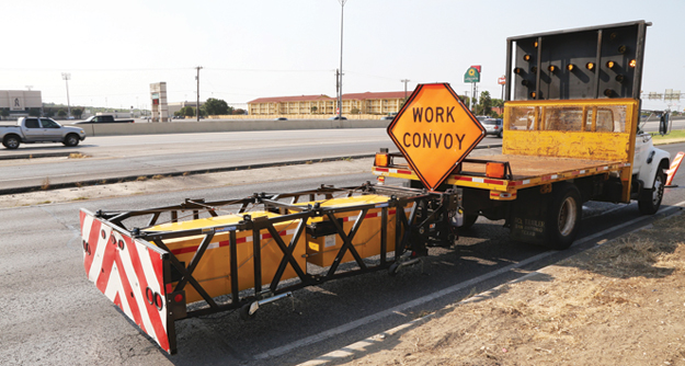 Truck with work convoy sign and directional arrow pointing left