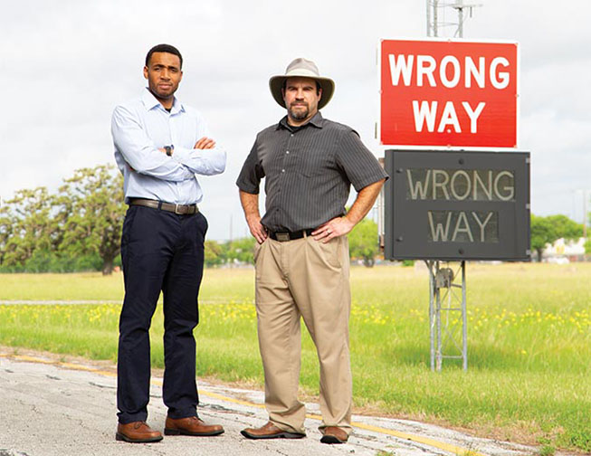 Authors standing next to "wrong way" street signs